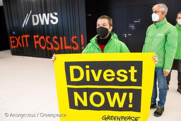 Eine Demonstrantin mit einem Schild bei einer Protestaktion im Eingangsbereich des Gebäudes der Deutsche-Bank-Fondstochter DWS in Frankfurt.