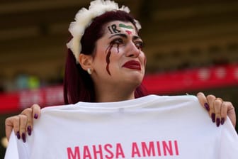 Iranische Anhängerin hält ein Trikot mit dem Namen der ermordeten Mahsa Amini: Vor der Vorrundenpartie gegen Wales weinten mehrere Fans hemmunglos auf den Rängen.