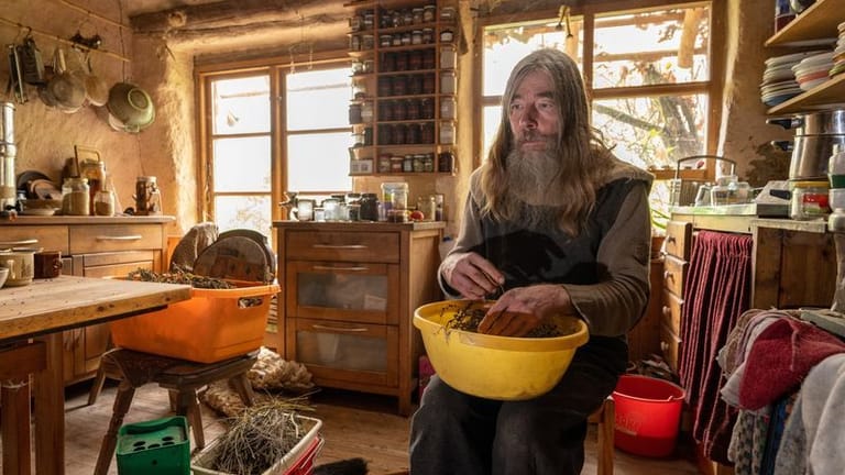 Friedmunt Sonnemann sitzt in der Küche seiner selbstgebauten Lehmhütte.