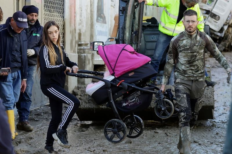 Ein Helfer trägt den Kinderwagen mit einer Frau nach schweren Stürmen auf Ischia.