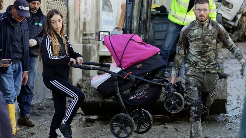 Ein Helfer trägt den Kinderwagen mit einer Frau nach schweren Stürmen auf Ischia.