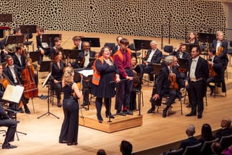 Zwei Aktivisten stehen auf der Bühne der Elbphilharmonie in Hamburg: Sie hatten sich am Dirigentenpult festgeklebt.