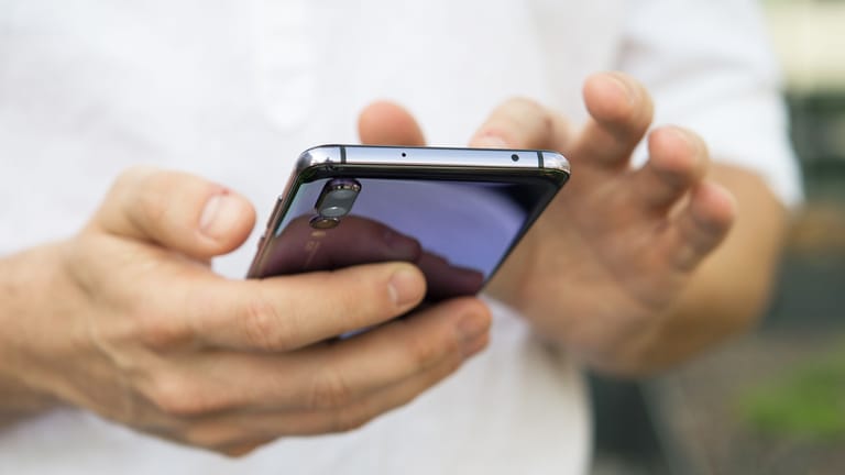 Ein Mann benutzt ein Smartphone (Symbolbild): Am 8. Dezember werden Millionen Testwarnmeldungen verschickt.