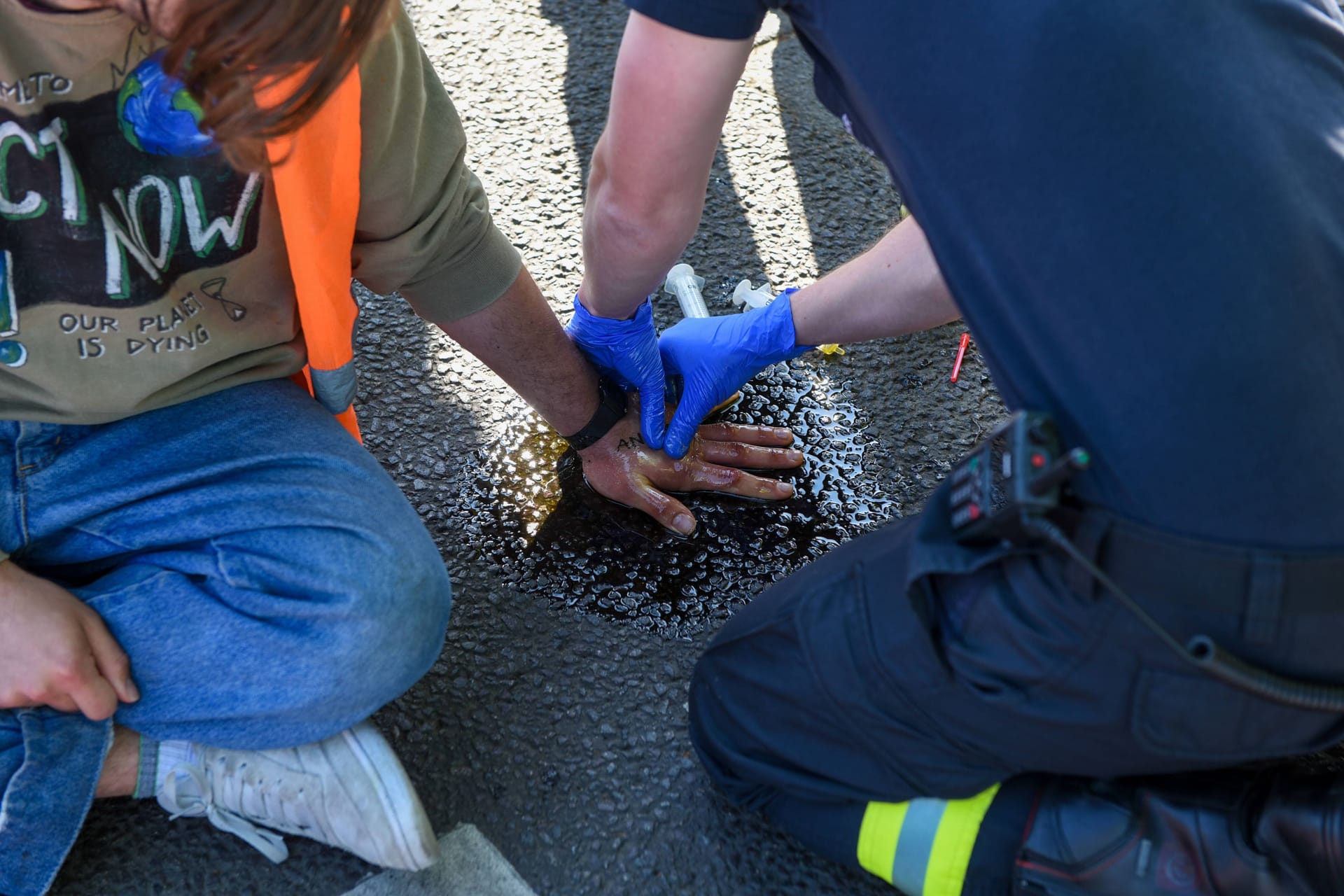 Einsatzkraft löst Klimakleber von der Straße: Dafür hat die Polizei München nun einen Preis angesetzt.