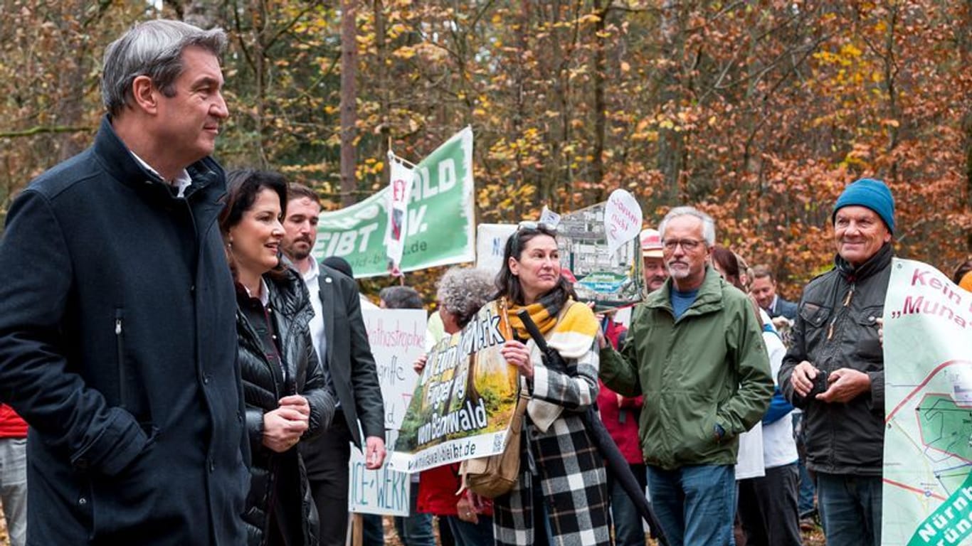 Markus Söder (vorne) und Michaela Kaniber (M, CSU) kommen im Reichswald an und werden von den Demonstranten "begrüßt".