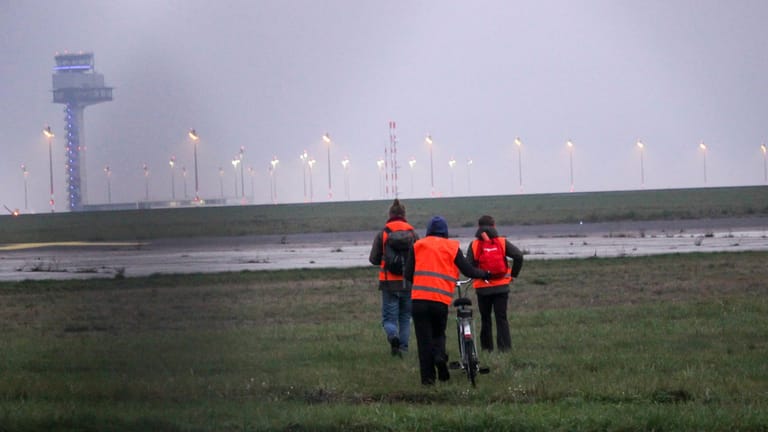 Aktivisten der "Letzten Generation" laufen auf das Gelände des Flughafens BER.