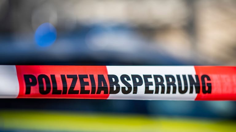 Ein Absperrband mit der Aufschrift "Polizeiabsperrung" ist vor einem Polizeiwagen aufgespannt (Symbolbild): In Oldenburg wurde eine weibliche Leiche gefunden.