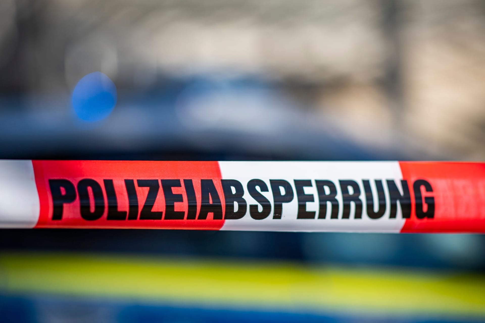Ein Absperrband mit der Aufschrift "Polizeiabsperrung" ist vor einem Polizeiwagen aufgespannt (Symbolbild): In Oldenburg wurde eine weibliche Leiche gefunden.