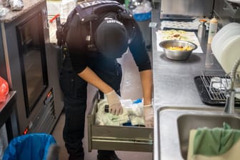 Ein Polizist durchsucht eine Schublade in der Küche des Imbisses: Die Fahnder konnten kleinere Mengen an Drogen sicherstellen.