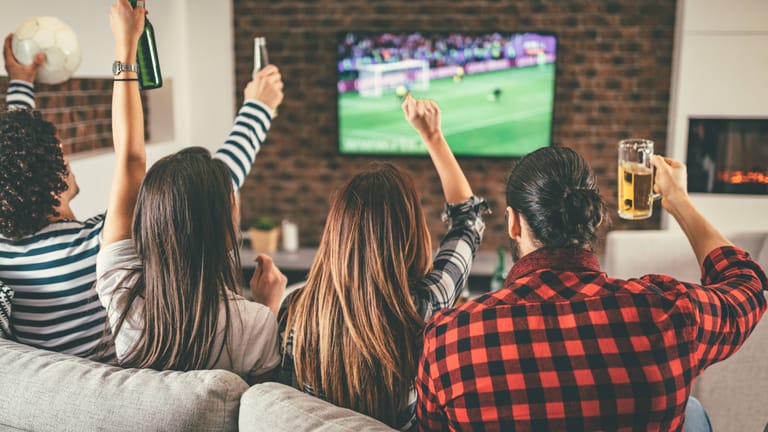 Fußballfans gucken gemeinsam Spiel: Im Winter verlagert sich Public Viewing in die heimischen Wohnzimmer.