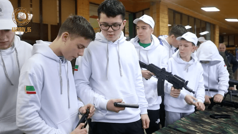 Die aus der Ukraine stammenden Jugendlichen schauen sich Pistolen und Gewehre an.
