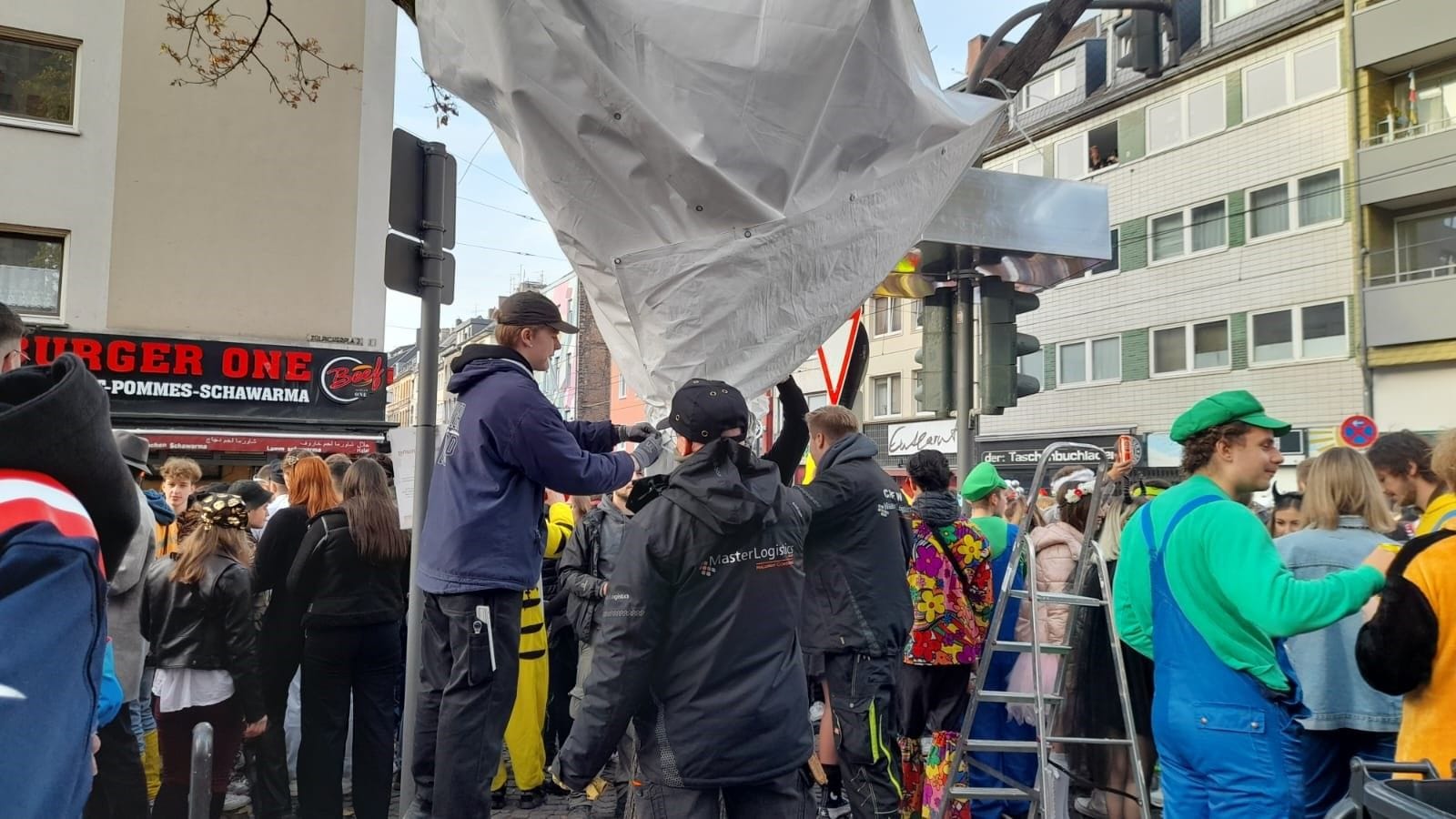 Am Zülpicher Platz: Ordnungskräfte umhüllen einen Baum, damit niemand auf ihn drauf klettern kann.