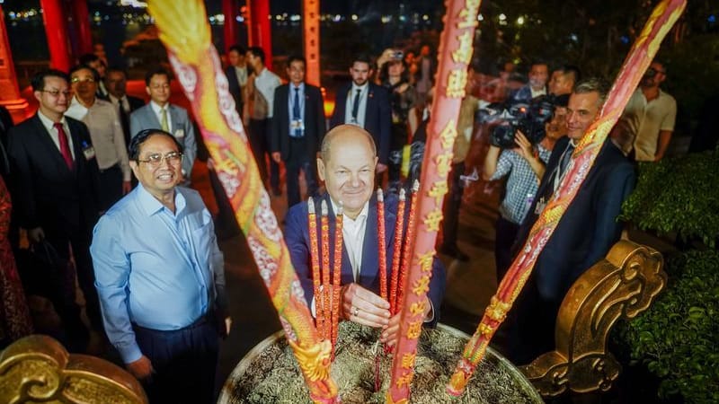 Scholz besucht in Hanoi einen Tempel und stell Räuchserstäbchen auf.