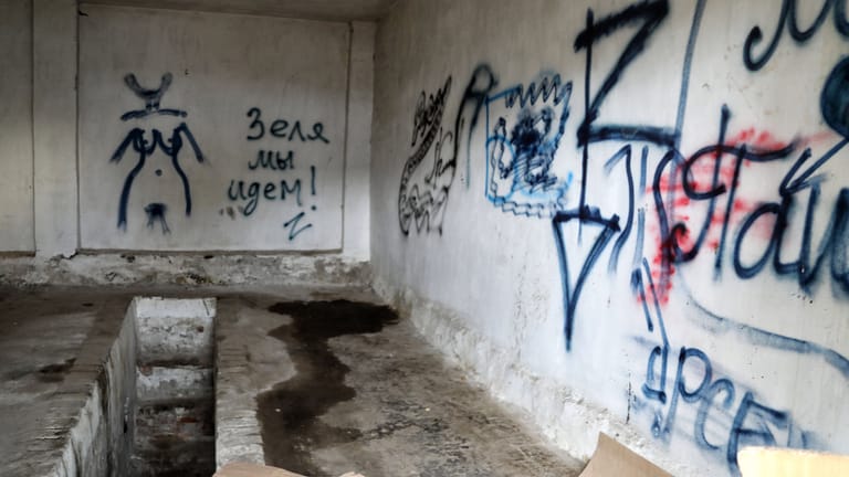 Im Inneren eines von den russischen Truppen genutzten Gefängnisses finden sich Graffiti an den Wänden und Spuren von Misshandlungen.