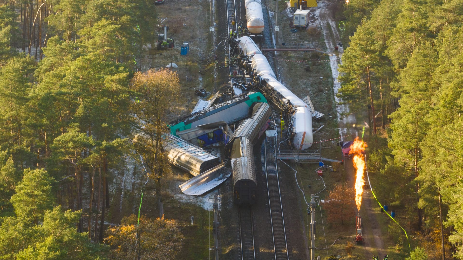 Beschädigte Waggons auf dem Bahndamm, während Gas abgefackelt wird (Archivbild): Pro Bahn kritisiert die Deutsche Bahn aufgrund der Fahrgastinformationen nach der Streckensperrung.