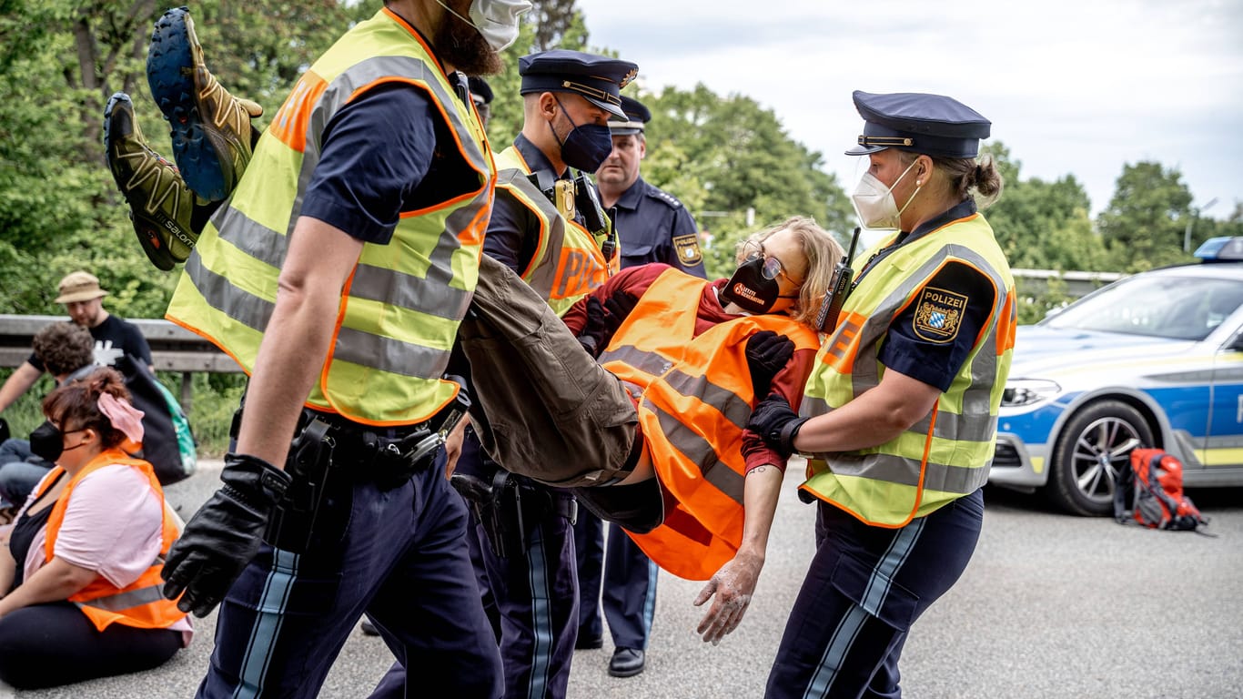 Münchner Einsatzkräfte tragen Aktivisten der "Letzten Generation" nach einer Blockade von der Straße. (Archivbild)