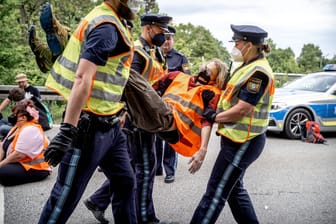Münchner Einsatzkräfte tragen Aktivisten der "Letzten Generation" nach einer Blockade von der Straße. (Archivbild)