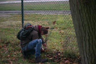 Ein Aktivist der "Letzten Generation" durchschneidet den Zaun am BER-Gelände.