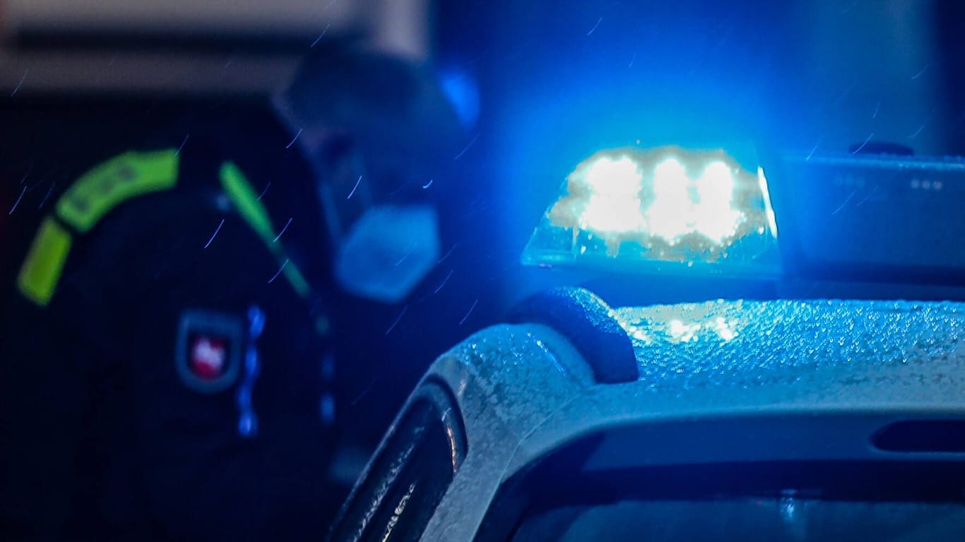 Ein Polizist vor einem Einsatzwagen mit Blaulicht (Symbolfoto): Die Beamten glauben, der Senior wurde bereits länger beobachtet.