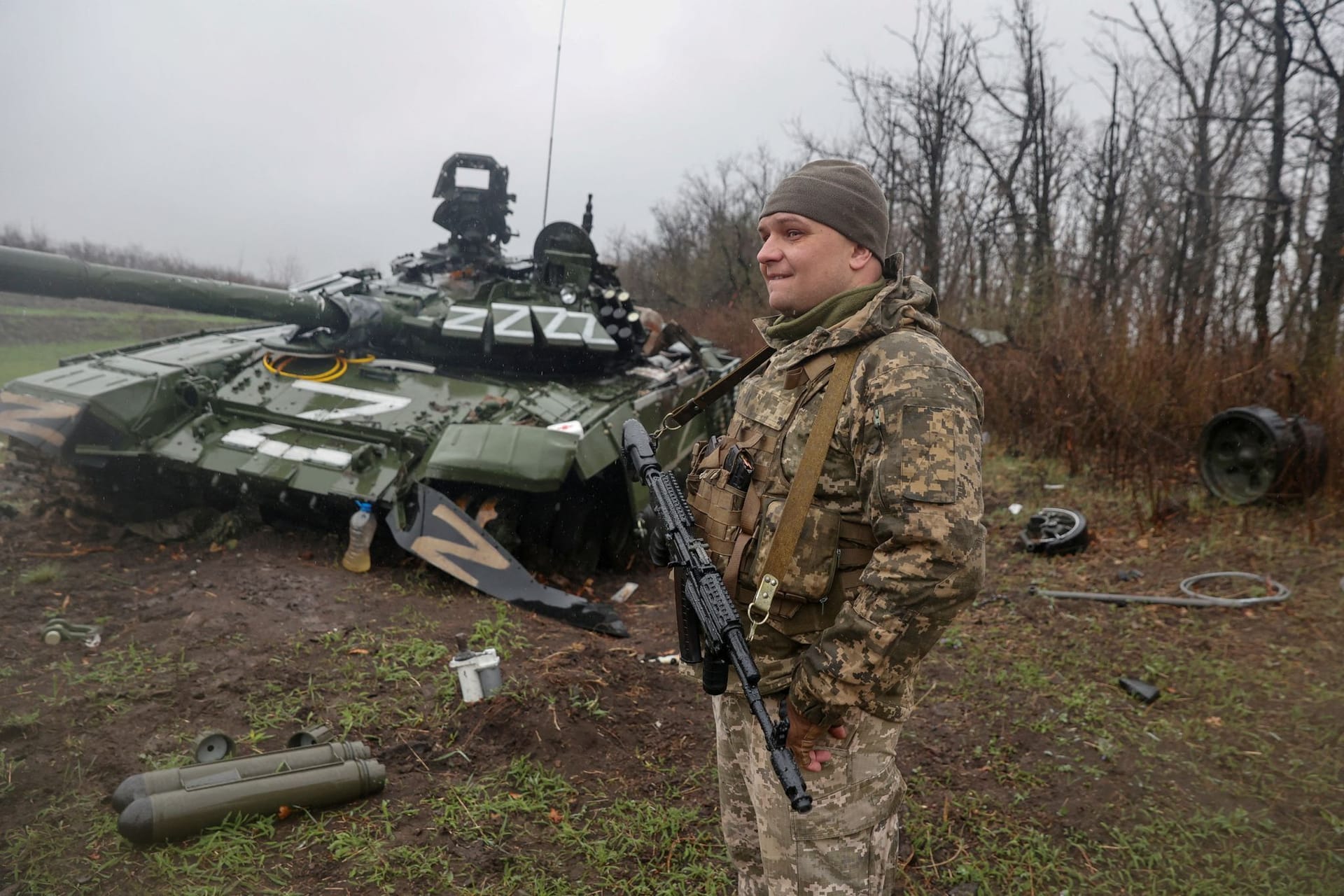 Ein ukrainischer Soldat steht neben einem zerstörten russischen Panzer.