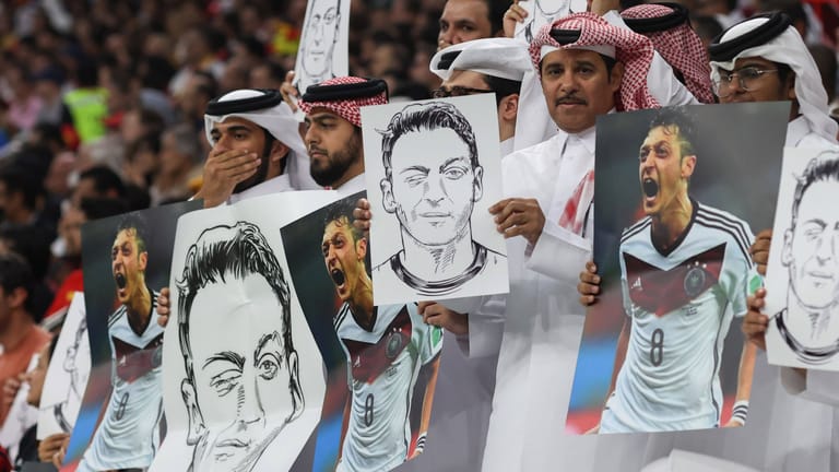 Szenen aus dem Al-Bayt-Stadion: Zuschauer halten Plakate mit Mesut Özil drauf in die Luft.