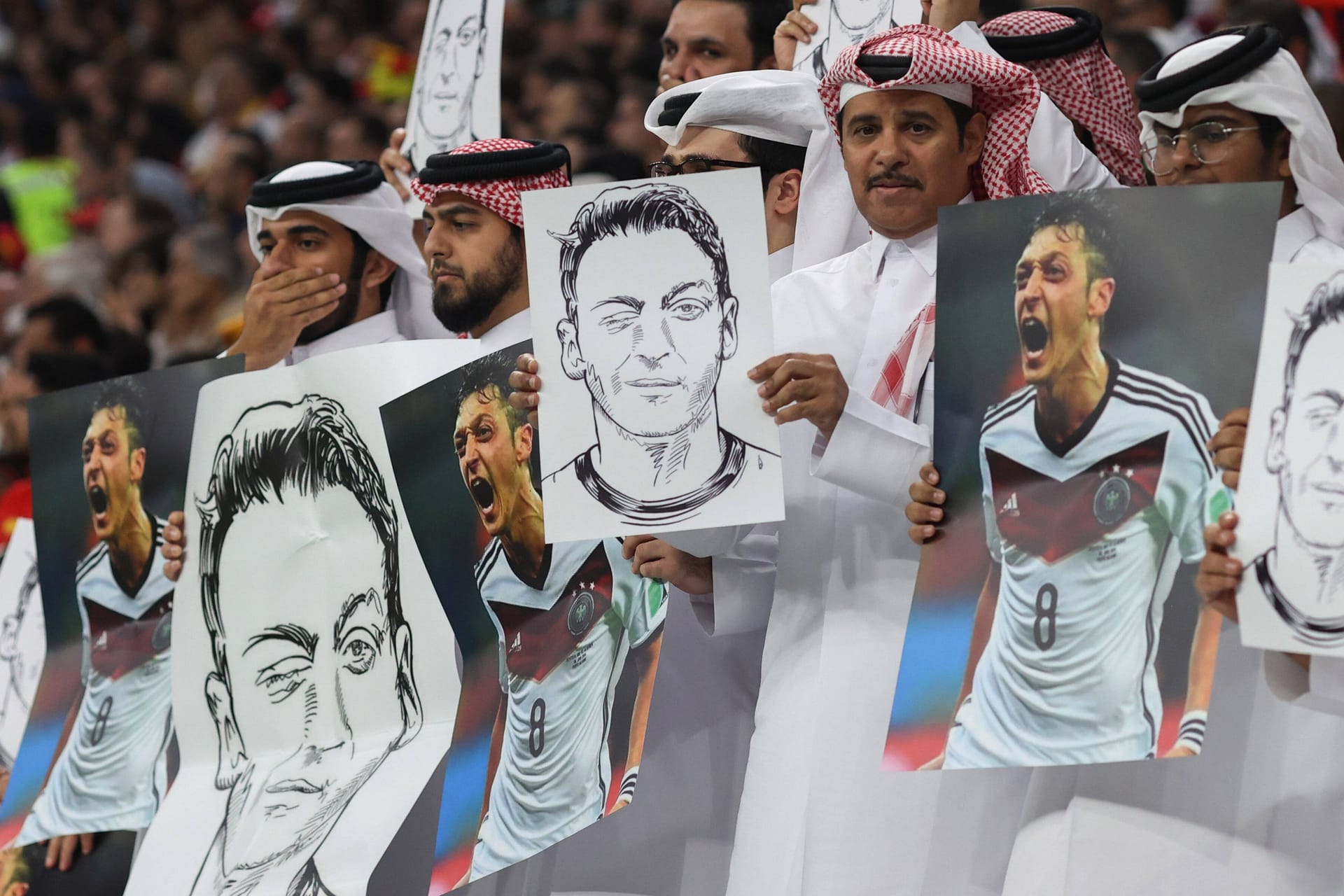 Szenen aus dem Al-Bayt-Stadion: Zuschauer halten Plakate mit Mesut Özil drauf in die Luft.