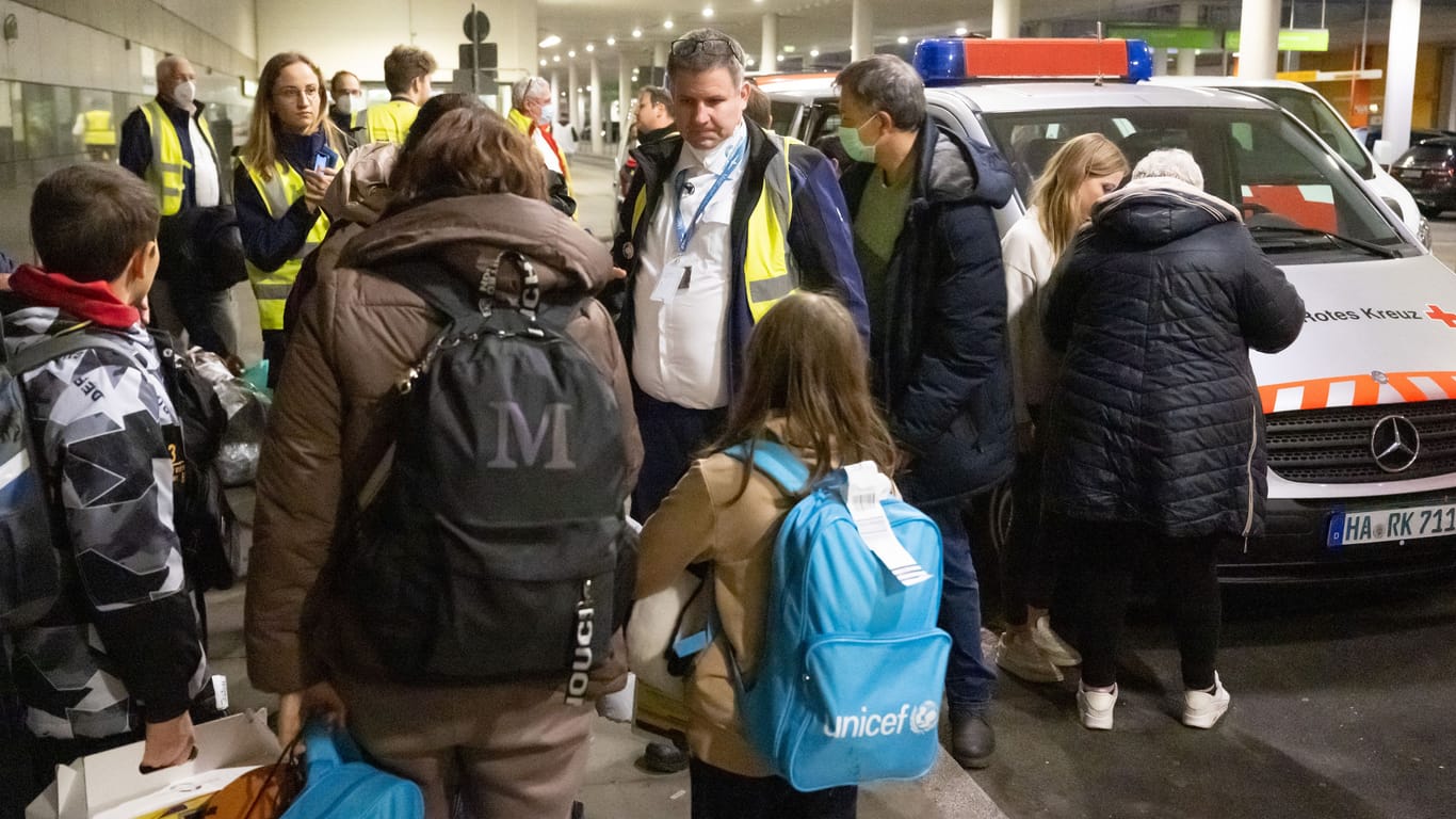 Evakuierte ukrainische Kriegsfüchtlinge warten nach einem Flug aus Moldavien am Flughafen auf den Weitertransport in Fahrzeugen des Deutschen Roten Kreuzes und des Arbeiter-Samariter-Bundes zu einer Erstaufnahmeeinrichtung. Helfer kümmern sich dabei um die Flüchtlinge.
