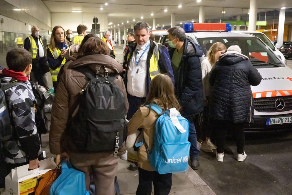Evakuierte ukrainische Kriegsfüchtlinge warten nach einem Flug aus Moldavien am Flughafen auf den Weitertransport in Fahrzeugen des Deutschen Roten Kreuzes und des Arbeiter-Samariter-Bundes zu einer Erstaufnahmeeinrichtung. Helfer kümmern sich dabei um die Flüchtlinge.