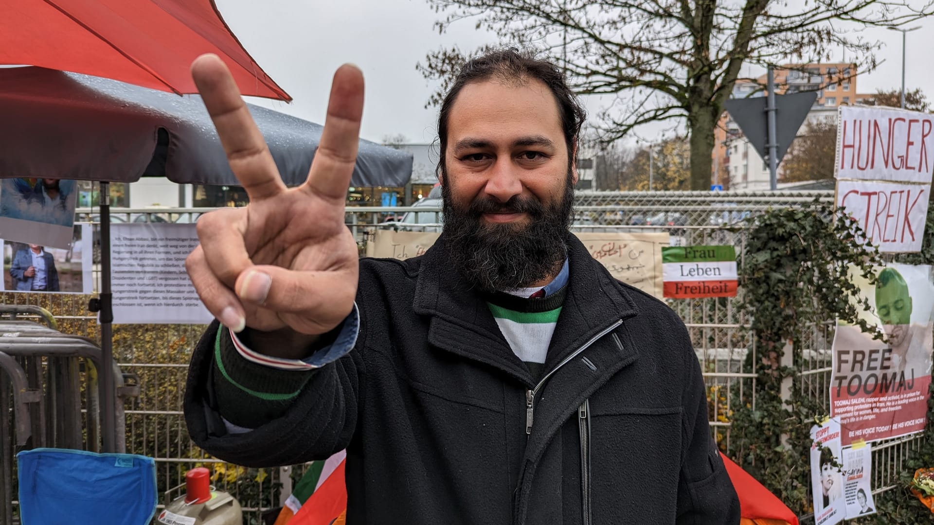 Der Iraner Ehsan Abasi vor seinem kleinen Camp: Er will so lange protestieren bis das Konsulat schließt.