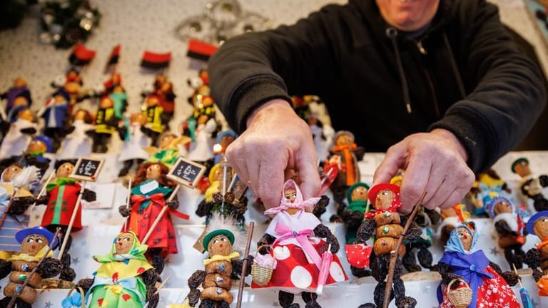 Klaus Schrödel hält an seinem Stand auf dem Nürnberger Christkindlesmarkt Zwetschgenmännla in den Händen.