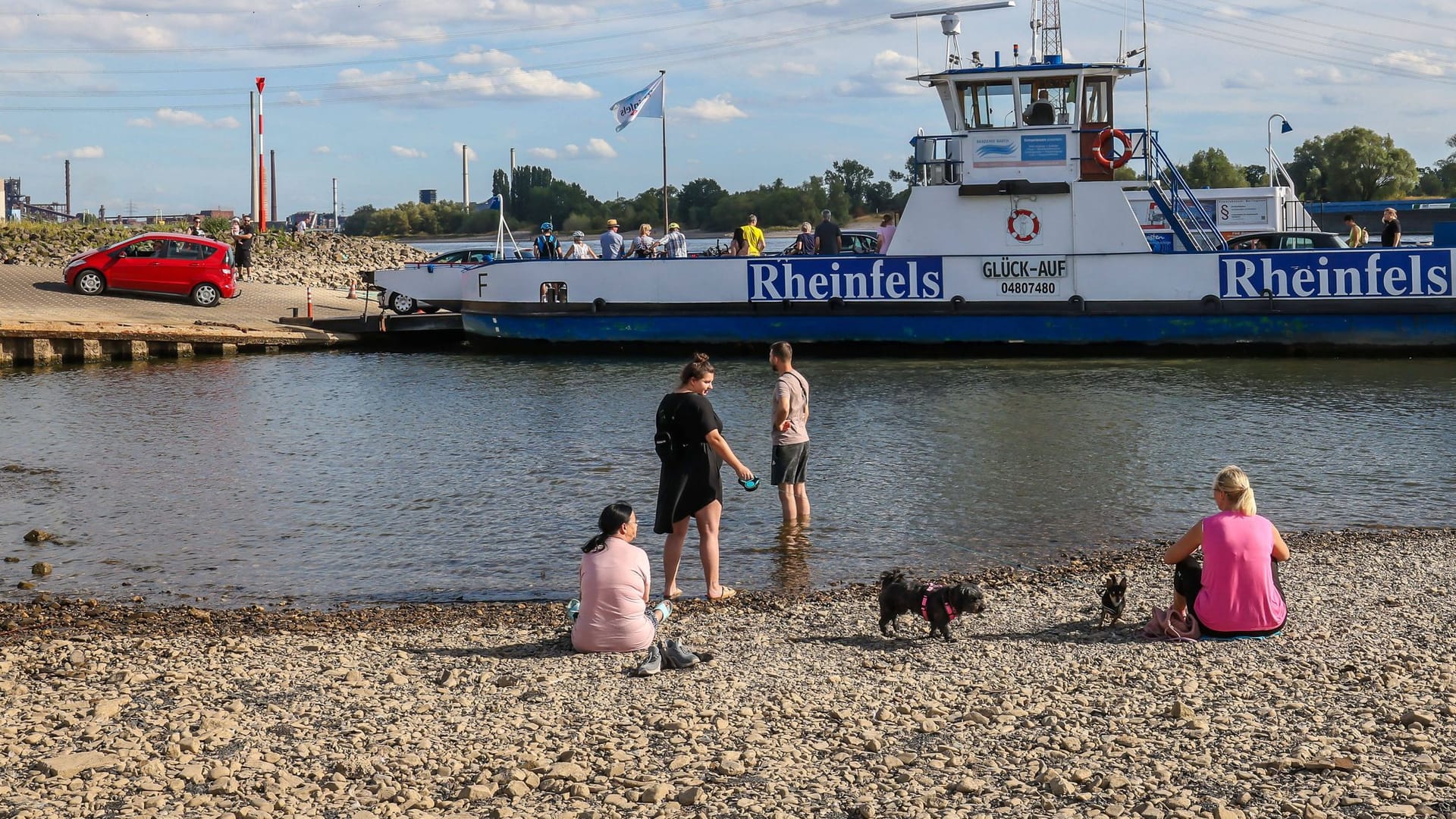 Menschen sitzen im ausgetrockneten Flussbett des Rheins im Sommer 2022: Allein in Deutschland gab es mindestens 4.500 Hitzetote.