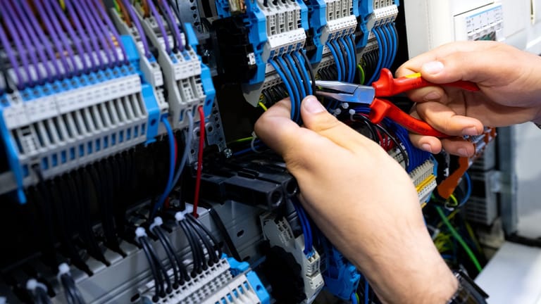 Ein Elektrohandwerker arbeitet an einem Stromkasten (Symbolfoto): Der Fachkräftemangel ist in vielen Branchen spürbar.