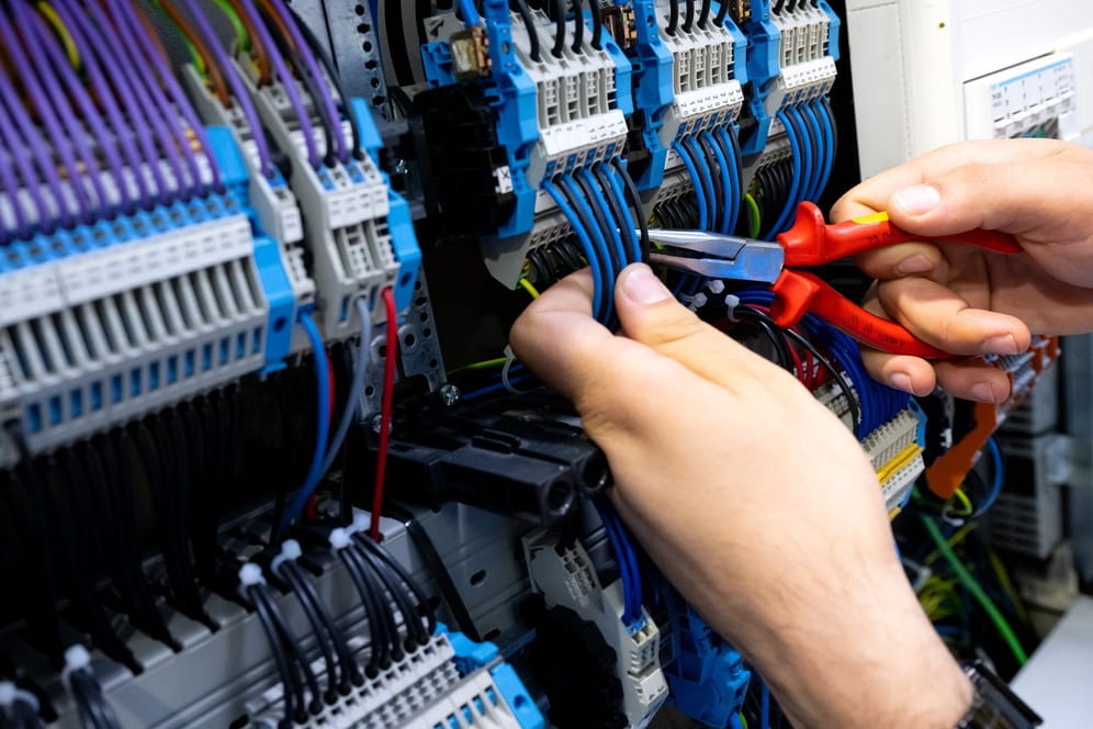 Ein Elektrohandwerker arbeitet an einem Stromkasten (Symbolfoto): Der Fachkräftemangel ist in vielen Branchen spürbar.