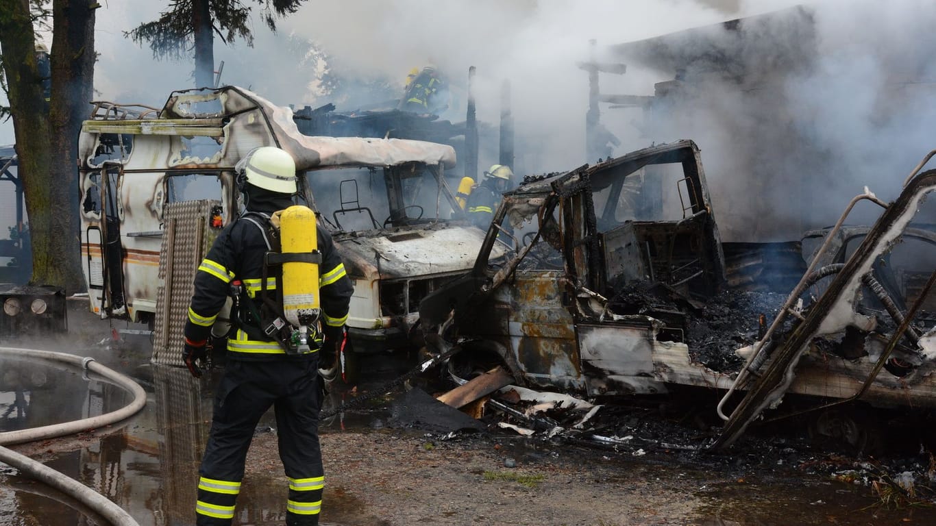Ein Feuerwehrmann steht vor den ausgebrannten Fahrzeugen: Eine Person fiel den Flammen zum Opfer.