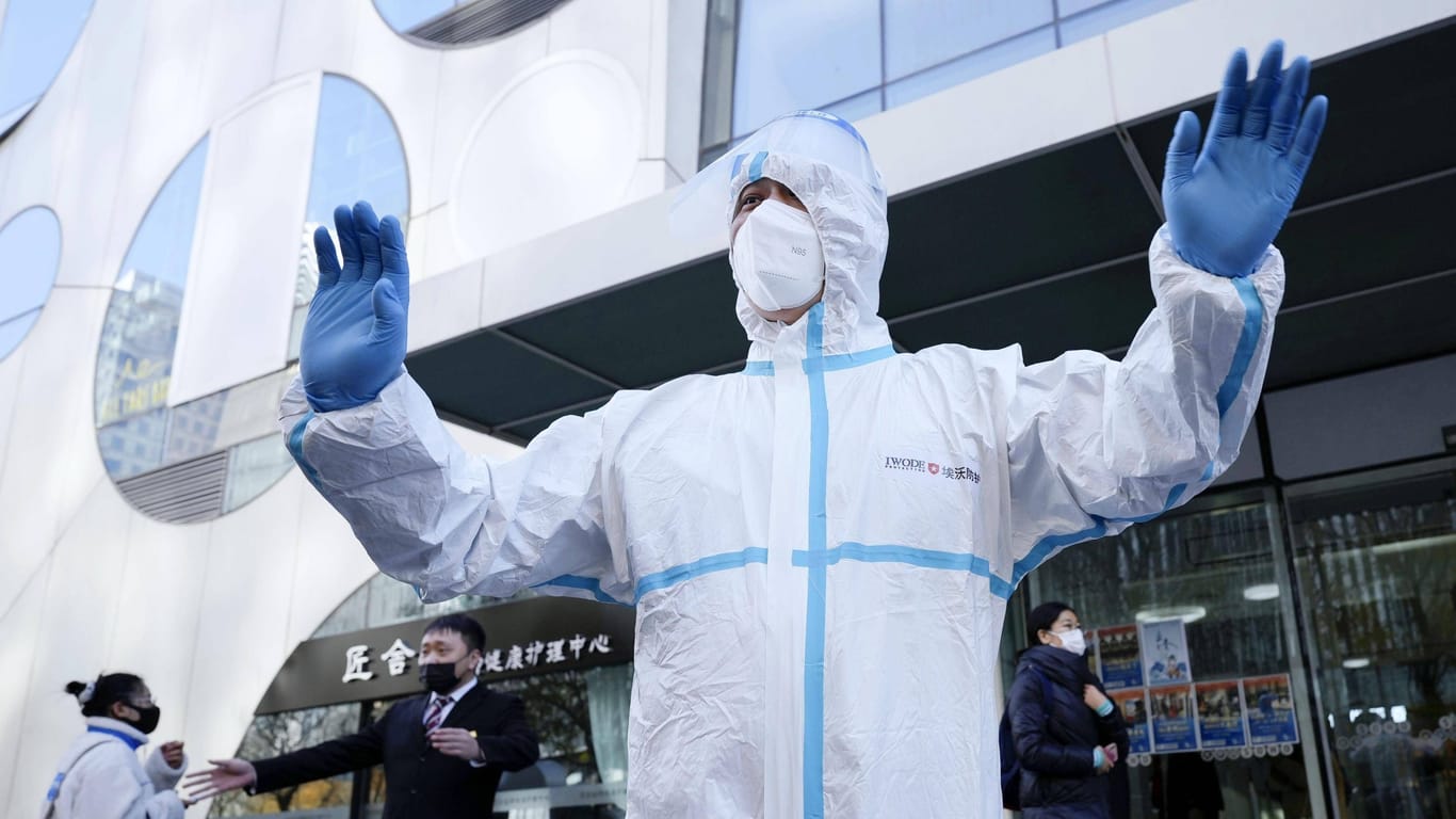 Ein Mann in Schutzkleidung vor einem wegen des Coronavirus gesperrten Gebäude in Peking: Die Regierung erlaubt bei milden Corona-Fällen künftig Quarantäne zu Hause.