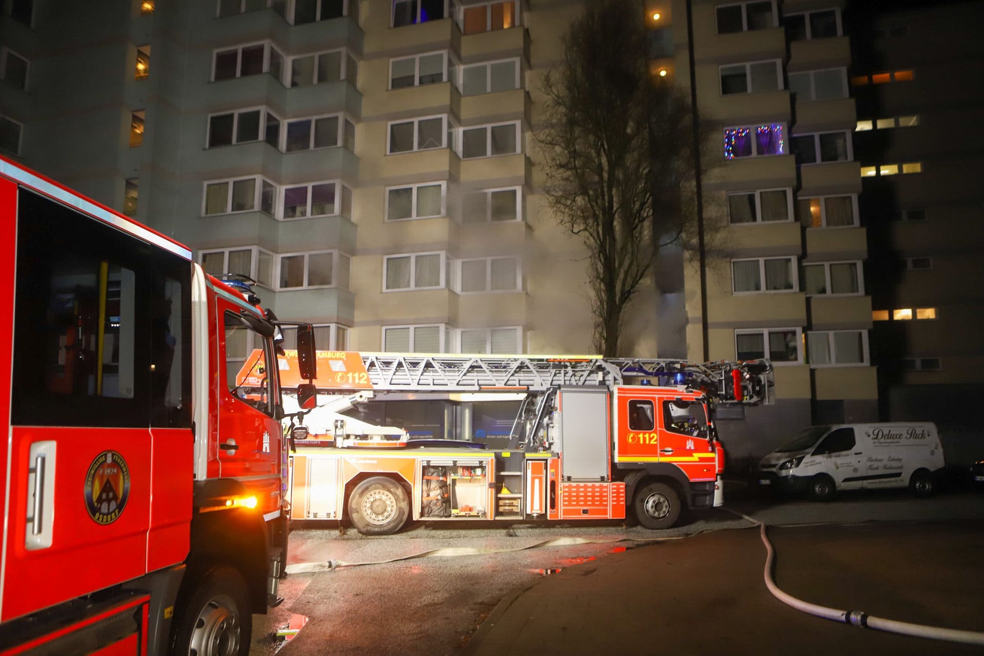 Einsatzkräfte der Feuerwehr am Hochhaus: Rauchschwaden kommen aus der Wohnung.