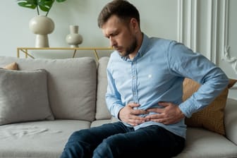 Mann mit Bauchschmerzen auf Couch