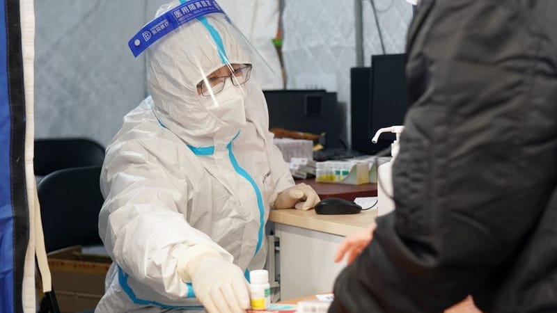 Peking: Ein Mitarbeiter einer behilfsmäßigen Fieberklinik in einer Turnhalle gibt Medizin an einen Fieberkranken aus.