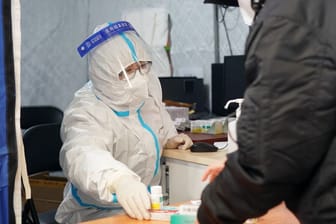 Peking: Ein Mitarbeiter einer behilfsmäßigen Fieberklinik in einer Turnhalle gibt Medizin an einen Fieberkranken aus.