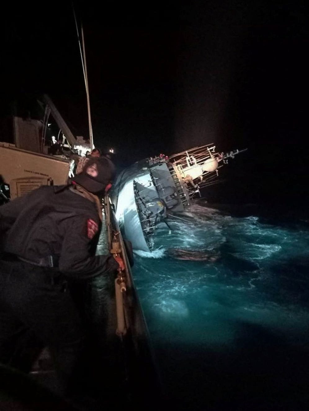 A marine looks at the capsized HTMS Sukhothai warship in the Gulf of Thailand
