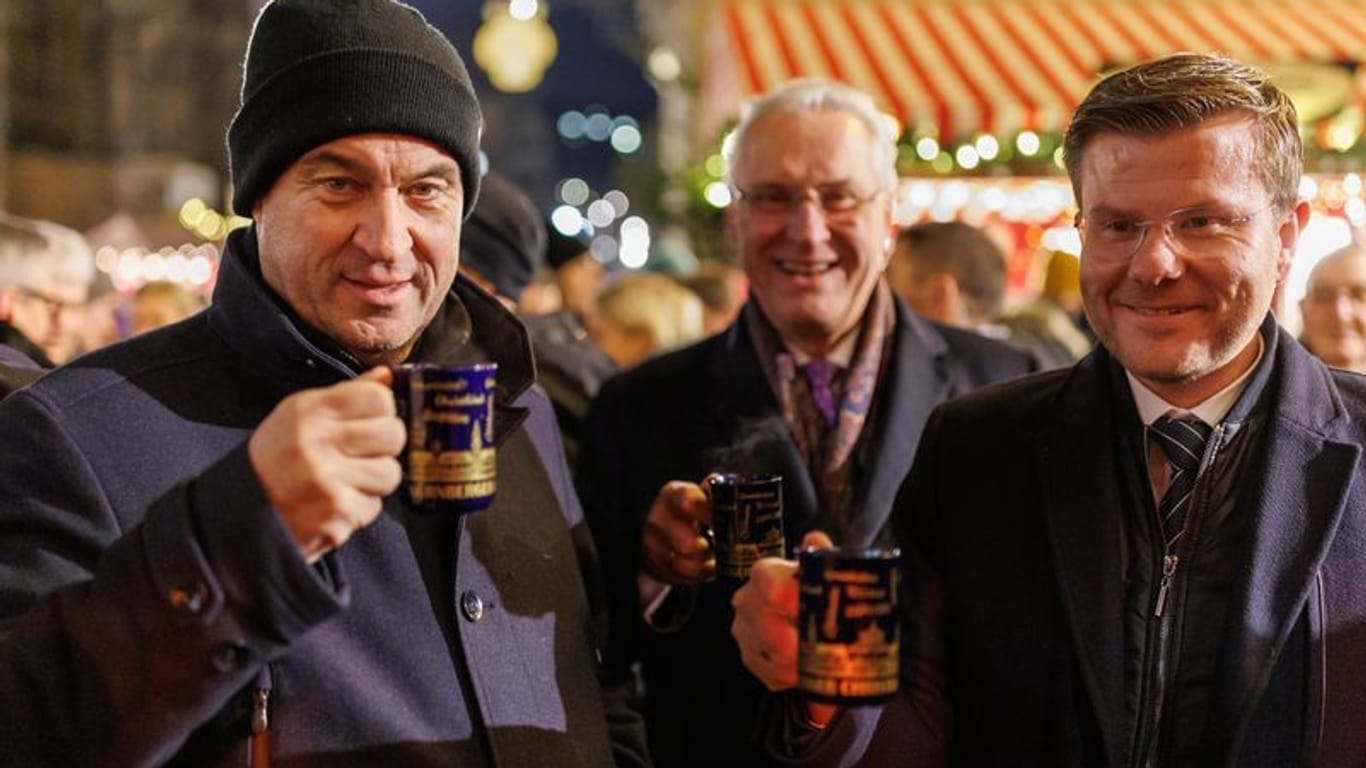 Ministerpräsident Markus Söder, Innenminister Joachim Herrmann und OB Marcus König (von links nach rechts) trinken nach der Kabinettssitzung Kinderpunsch auf dem Christkindlesmarkt.