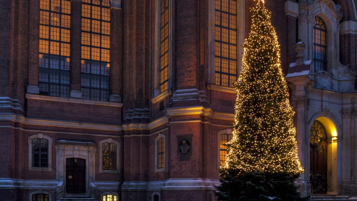 Ein beleuchteter Weihnachtsbaum steht vor einer Kirche (Symbolbild): In den nächsten Tagen wird es wohl keinen Schnee mehr geben.