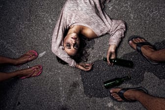 Eine betrunkene Frau liegt auf dem Boden.