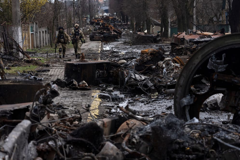 Zwei ukrainische Soldaten gehen auf einer Straße, die übersät ist mit zerstörten russischen Militärfahrzeugen: In der ukrainischen Stadt Butscha, 25 Kilometer nordwestlich der Hauptstadt Kiew, bietet sich nach dem Rückzug der russischen Armee ein Bild des Grauens.