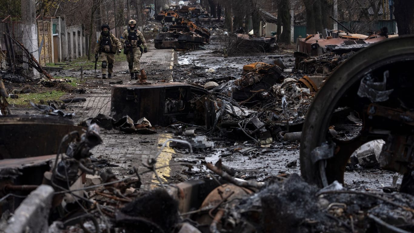 Zwei ukrainische Soldaten gehen auf einer Straße, die übersät ist mit zerstörten russischen Militärfahrzeugen: In der ukrainischen Stadt Butscha, 25 Kilometer nordwestlich der Hauptstadt Kiew, bietet sich nach dem Rückzug der russischen Armee ein Bild des Grauens.