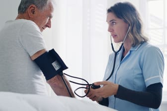 Ärztin misst den Blutdruck eines Mannes