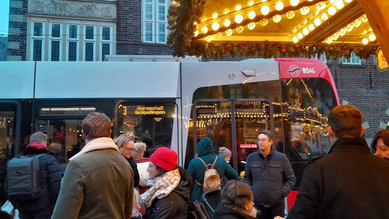 Eine Straßenbahn der Linie 3 fährt direkt an Weihnachtsmarkt-Besuchern vorbei: Das kann schon mal wuselig werden.