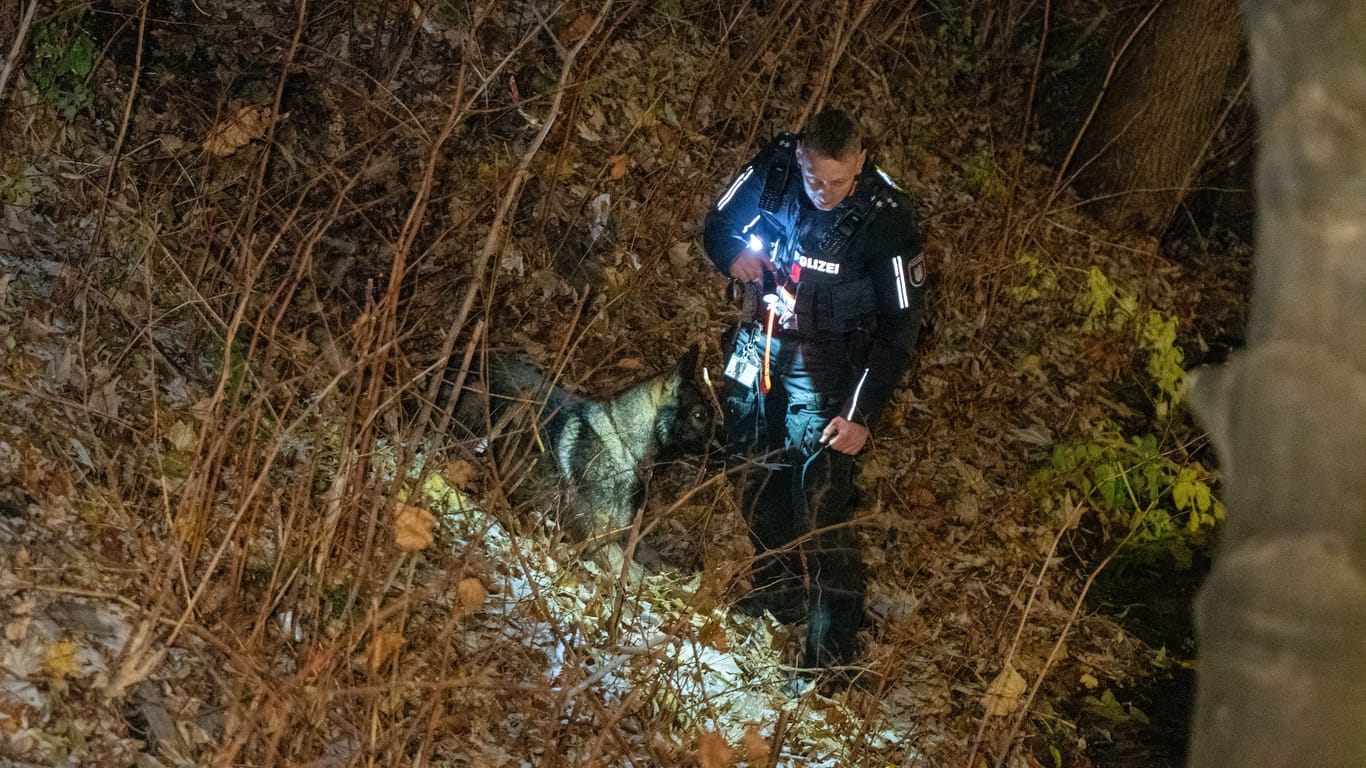 Ein Polizist sucht mit einem Spürhund eine Uferböschung ab: Die Ermittler suchten nach Diebesgut am Mittelkanal in Hamburg.