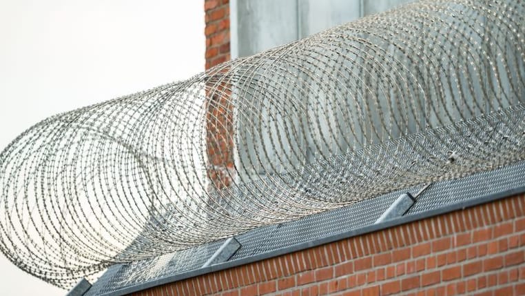 Stacheldraht an einer JVA (Symbolfoto): 2022 bekamen zu Unrecht inhaftierte Menschen insgesamt Entschädigungen in Höhe von rund 173.000 Euro ausgezahlt.