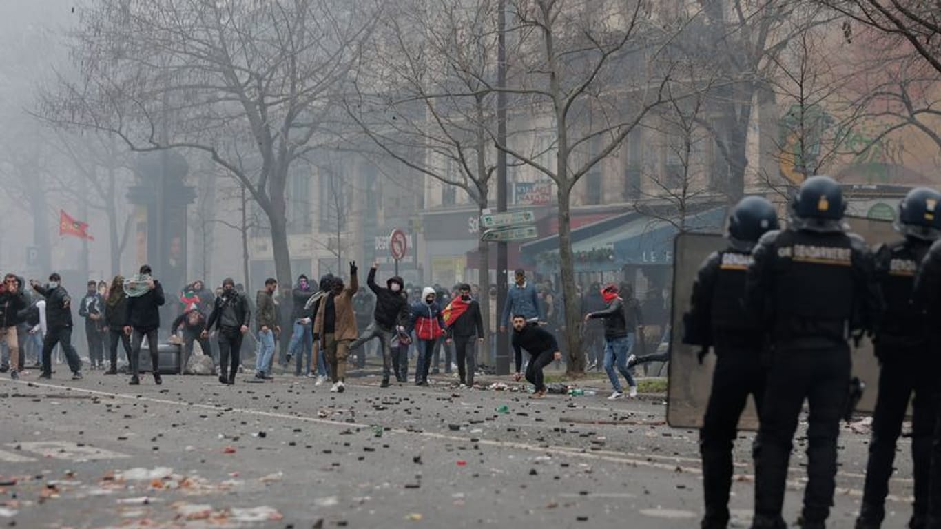 Bei Protesten in Paris werden Polizisten mit Steinen beworfen.